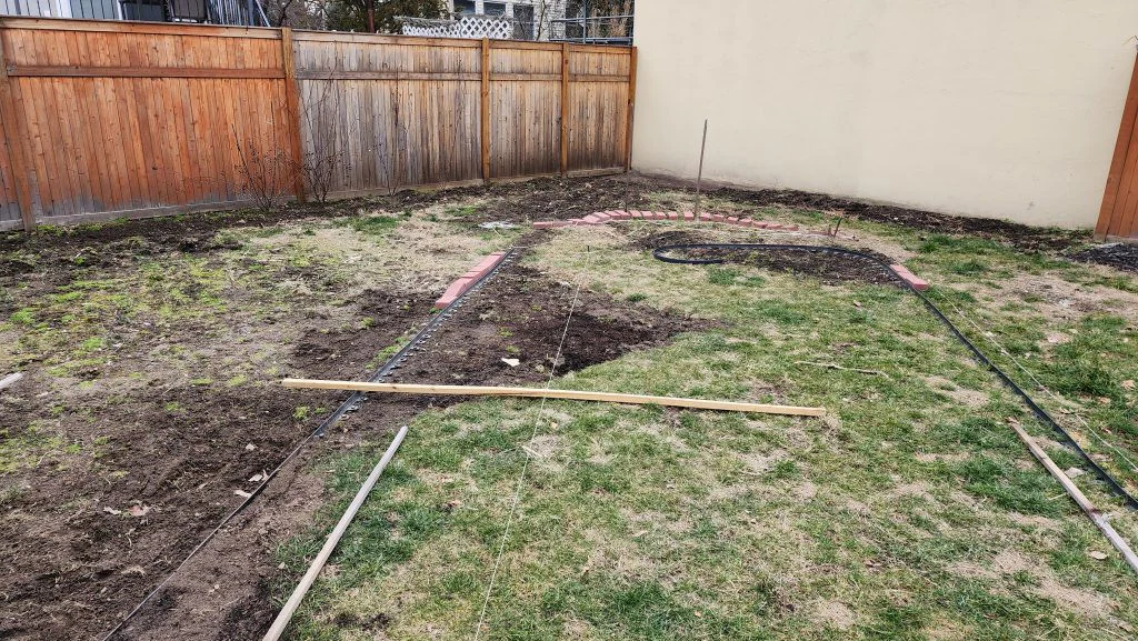 The new center lawn path being laid out with string lines, plastic edging, and test bricks